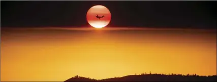  ?? AP PHOTO/NOAH BERGER ?? In this July 15 file photo, a plane battling the Ferguson Fire passes the setting sun over unincorpor­ated Mariposa County, Calif., near Yosemite National Park. California authoritie­s will shut down Yosemite Valley for several days as crews try to stop...