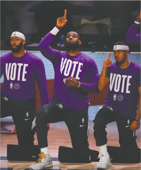  ?? Mike Ehrman / Gett y Images ?? Anthony Davis, Lebron James and Quinn Cook of the Los Angeles Lakers kneel during the U. S. national anthem before taking the court against the Denver Nuggets in Game Three of the Western Conference Finals on Sept. 22.