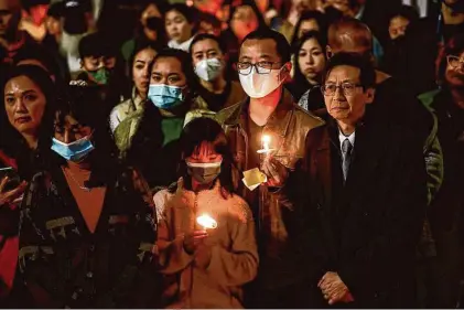  ?? Gabrielle Lurie/The Chronicle ?? Leto Sze, 9, (center) and father Michael Sze (right) attend a vigil on Jan. 25 in Oakland for the recent mass shooting victims.