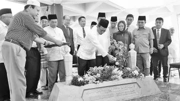  ??  ?? Shafie scattering flowers on the grave of Tun Mohd Fuad Stephens at the Sabah State Mausoleum.