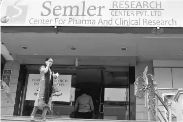  ??  ?? A woman talks on a mobile phone as she walks past the closed research facility of Semler Research Centre in Bengaluru, India. — Reuters photo