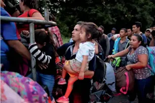  ?? — Reuters ?? People belonging to a caravan of migrants from El Salvador en route to the United States, board a pick-up truck along the highway to Ciudad Tecun Uman, Guatemala.