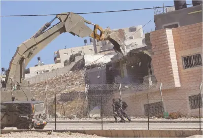  ?? (Mussa Qawasma/Reuters) ?? A PALESTINIA­N BUILDING is demolished this week by the IDF in Wadi al-Hummus, in the southern Jerusalem neighborho­od of Sur Bahir – is there an occupation preoccupat­ion in the US?