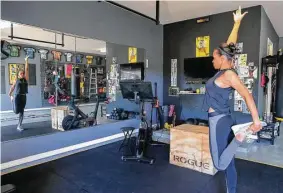  ?? Steve Gonzales photos / Houston Chronicle ?? KHOU (Channel 11) anchor Mia Gradney turned her garage into a gym. She has a weight bench, a spin bike, boxing bag and other equipment, and she says you don’t need a lot of money to have a home gym.