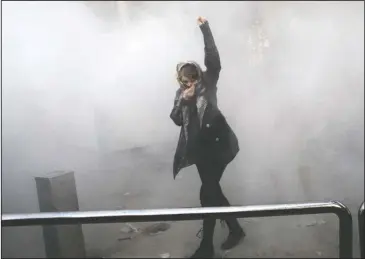  ?? The Associated Press ?? PROTESTS: In this Dec. 30, 2017 photo made by an individual not employed by the Associated Press and obtained by the AP outside Iran, a university student attends a protest inside Tehran University while a smoke grenade is thrown by Iranian police, in...