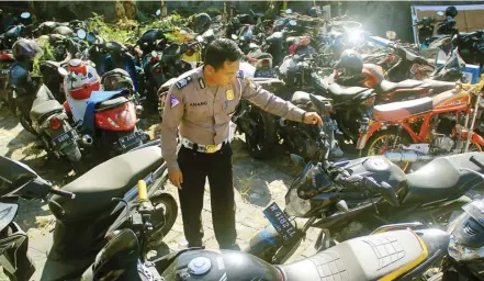  ?? ADI WIJAYA/JAWA POS ?? CEK KONDISI: Anggota unit laka satlantas mengecek kondisi barang bukti sepeda motor di kantor Satlantas Polres Gresik.