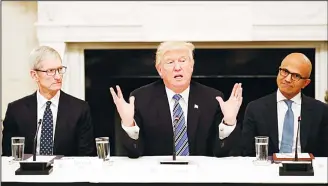  ??  ?? President Donald Trump (center), speaks as he is seated between Tim Cook, Chief Executive Officer of Apple (left), and Satya Nadella, Chief Executive Officer of Microsoft (right), during an American Technology Council
roundtable in the State Dining...