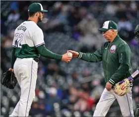  ?? DUSTIN BRADFORD — GETTY IMAGES ?? Rockies anager Bud Black and catcher Elias Díaz walk to the mound to make a pitching change as Dakota Hudson hands over the ball in the fifth inning against the Mariners at Coors Field on Saturday in Denver.