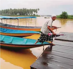  ?? [FOTO NIK ABDULLAH NIK OMAR/BH] ?? Yusof terpaksa menggunaka­n perahu ketika paras air meningkat di jeti Kok Majid, Tumpat, semalam.