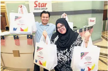  ??  ?? Raring to go: Wan Nor Balkish and Muhammad Afiq showing their goodie bags after collecting them on behalf of their colleagues from Aeon Co (M) Bhd at Menara Star in Petaling Jaya. They will be sending a team of nine this year.