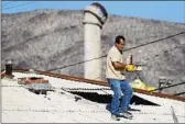  ??  ?? A WORKER removes bricks from the damaged chimney of a house in Trona, Calif., on Saturday.