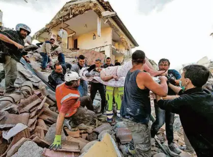  ?? Massimo Percossi/ANSA via AP ?? Equipes de resgate retiram mulher de escombros de edifício que desmoronou na cidade de Amatrice, a 150 km de Roma; região é pouco habitada, mas terreno montanhoso dificulta a ação de bombeiros