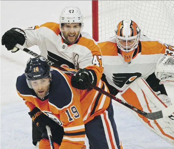  ?? LARRY WONG ?? Edmonton Oilers left wing Patrick Maroon is checked by Philadelph­ia Flyers defenceman Andrew MacDonald in front of Flyers goalie Brian Elliott during the first period on Wednesday night at Rogers Place. Elliott made 24 saves as the Flyers won 4-2.