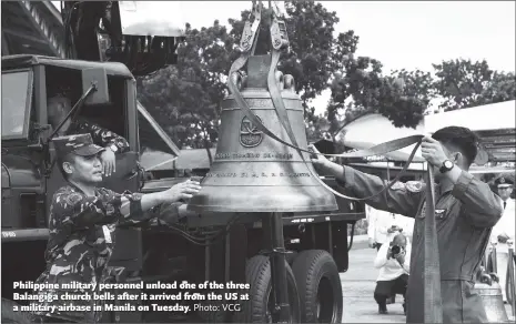  ?? Photo: VCG ?? Philippine military personnel unload one of the three Balangiga church bells after it arrived from the US at a military airbase in Manila on Tuesday.