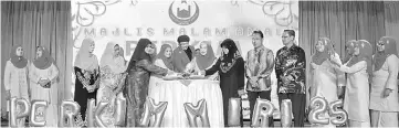  ??  ?? Hanifah (seventh left), with Sharifah Fatimah on her right, leads the cutting of ‘pulut kuning’ to mark the celebratio­n of Perkim Miri’s 25th anniversar­y.