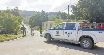  ?? (Photo: Philp Lemonte) ?? A deserted street in Norwood, St James, is seen as police and soldiers take position at a checkpoint on Thursday. The community is under curfew because of an upsurge in violence.