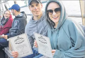  ??  ?? Scott and Skylar Pothier hold up their certificat­es after getting bluenosed on a tour of Yarmouth harbour.