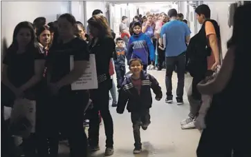  ??  ?? RECENTLY RELEASED migrants fill the hallways at the Catholic Charities Humanitari­an Respite Center, where volunteers provided them food, a place to sleep and transporta­tion to the McAllen Central Bus Station.