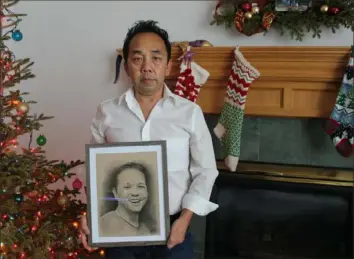  ?? Samantha Schmidt/The Washington Post ?? Eh Xiong holds a portrait of his late brother in his home, in December, in Woodbury, Minn.