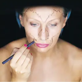  ??  ?? She draws strategic lines on her face with a makeup pencil.