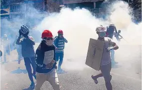  ?? ASSOCIATED PRESS ?? Anti-coup protesters run from tear gas launched by security forces in Yangon, Myanmar, on Monday, determined to continue their protests against military’s power grab.