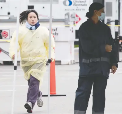  ?? JONATHAN HAYWARD / THE CANADIAN PRESS ?? A health-care worker runs through the parking lot of a COVID-19 testing area in Burnaby, B.C., on Wednesday.