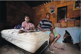  ?? ?? Bruno Ferreira and his son Davi sit on their only bed March 22 in their one-room home built by them in the Sol Nascente neighborho­od.