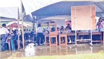  ??  ?? The students at SK Pekan Telupid seen attending class under canopies amidst rain on the first day of school this year.