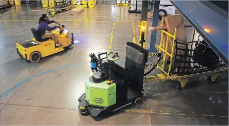  ?? TRAVIS DOVE NEW YORK TIMES ?? A robotic tugger, right, with a load of packages rounds a corner inside a FedEx distributi­on centre in Kernersvil­le, N.C. Tuggers are creating more jobs.