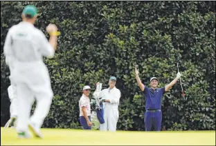  ?? Matt Slocum The Associated Press ?? Rickie Fowler, left, watches Jon Rahm rejoice after a hole-in-one on No. 16 during a practice round Tuesday for the Masters in Augusta, Ga.