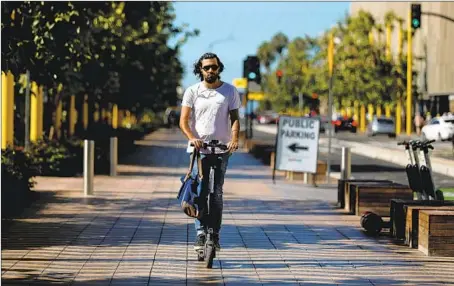  ?? Gary Coronado Los Angeles Times ?? A RIDER maneuvers an electric scooter in Santa Monica, which has a pilot program for the vehicles. Beverly Hills banned them in July.