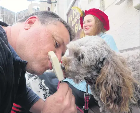  ?? PHOTO: SHANNON GILLIES ?? Going to the dogs . . . Ice cream and ice block creator Shaun Osborne with Tuppence the dog, a fan of his new Ice Dog Block creation for dogs, in Harbour St, Oamaru. Tuppence’s owner, Oamaru artist Donna Demente, looks on.