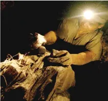  ??  ?? A MINER checks gold ore inside a mine in Itogon.