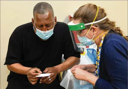  ?? BARBARA HADDOCK TAYLOR/BALTIMORE SUN/TNS ?? Bernard Segar of Baltimore receives a proof-of-vaccinatio­n card after receiving a Moderna vaccine from Dr. M. Catherine Mailander of Johns Hopkins Medicine at a vaccine clinic in East Baltimore’s Southern Baptist Church.