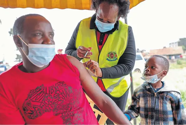  ??  ?? SHARING: A Kenyan man receives a dose of the AstraZenec­a coronaviru­s vaccine donated by Britain, as his son watches, in Nairobi.