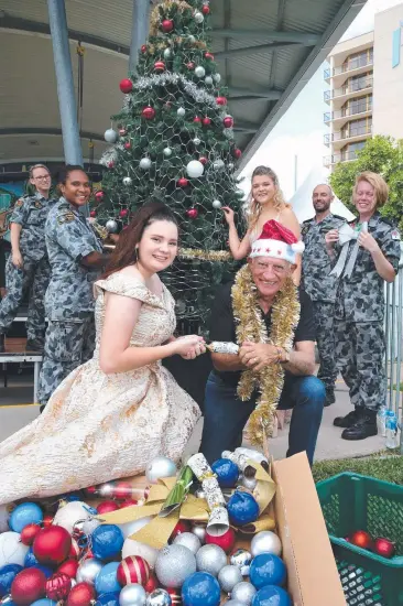  ?? Picture: ANNA ROGERS ?? FESTIVE: Performer Lily Bingham-Coop and Mayor Bob Manning pull a Christmas cracker as Navy volunteers LS Tegan Harwood, Seaman Jess Lowth, Seaman Travis Tedmanson and Seaman Kirsten Welham with performer Lauren Drent decorate the Christmas tree at Fogarty Park.