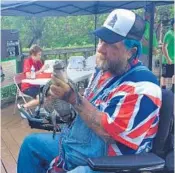  ?? MARCO SANTANA/STAFF ?? Willie Hendrickso­n, of San Diego, checks out a baby gator at the National Veterans Wheelchair Games at Gatorland.