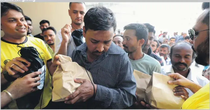  ?? Chris Whiteoak / The National ?? As part of its Ramadan health initiative, Century Financial Brokers hands out packs including food and hygiene products to labourers at Jebel Ali, Dubai