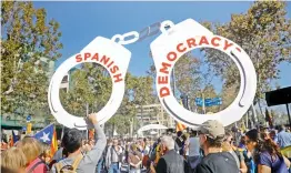  ??  ?? Protesters hold effigy of handcuffs as they take part a rally outside the Catalan Parliament in Barcelona, Spain, on Friday.