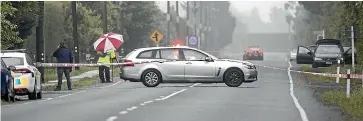  ?? GEORGE HEARD/ STUFF ?? A car is seen on the roadside, right, near where a police officer was run over in Darfield. Police opened fire on the driver after he hit the officer. At centre, a police photograph­er takes photos at the scene.