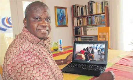  ?? FOTO: BRUNO JUNGWIRTH ?? Pfarrer Emanuel Sawadogo übernahm im September die Urlaubsver­tretung von Pfarrer Walter Stegmann in Riedlingen. Das Foto auf dem Laptop zeigt einen Blick in die neue Schneider-Schule, die er gegründet hat.