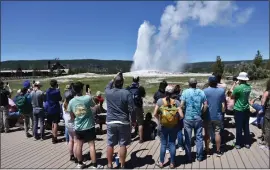  ?? MATTHEW BROWN — THE ASSOCIATED PRESS ?? The Old Faithful geyser erupts and shoots water and steam into the air as tourists watch and take photos in Yellowston­e National Park in Wyoming on Wednesday.