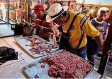  ??  ?? Food for thought: A customer smelling spoiled meat at a market in Maracaibo. — AP