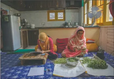  ??  ?? Kashmiri student Aaishya Imtiyaz writes her examinatio­n as her mother Nusrat Fatima cleans vegetables in their kitchen in Srinagar. “This is my second exam at home since last year. I hope and pray that we go to school very soon,” Aaishya said.