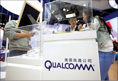  ?? AP ?? Visitors look at a display booth for Qualcomm at the Global Mobile Internet Conference in Beijing last spring. Shares of Qualcomm slid almost 5 percent Tuesday.