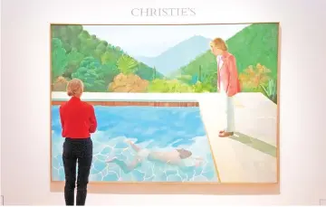  ??  ?? A woman looks at Hockney’s ‘Portrait of an Artist (Pool with Two Figures)’ during a press preview 8 at Christie’s New York. — AFP photo