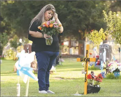  ?? (AP/Gary Kazanjian) ?? Lori Gonzalez wipes a tear away after visiting the temporary grave marker of her sister and Kaiser Permanente Fresno Medical Center nurse Sandra Oldfield, pictured right, at the Sanger Cemetery in Sanger, Calif.