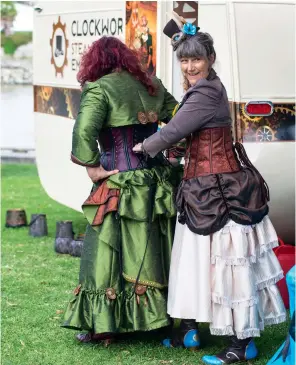  ??  ?? In her studio, steampunk heads and carriages rub shoulders with Lilliputia­n caravans that symbolize Lizzette’s lust for gypsy living. Friend and fellow steam punker Bronwyn Hughes, helps lace a leather corset to get the show on the road.