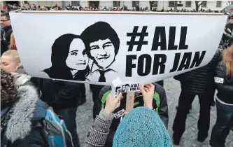  ?? RONALD ZAK THE ASSOCIATED PRESS ?? A woman attaches a sticker on a poster with a photo of slain journalist Jan Kuciak and his fiancée.