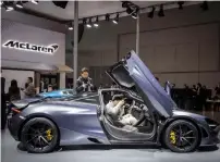  ?? — AP/ Bloomberg ?? Visitors look at an electric sports car from Chinese startup NIO during the Auto Shanghai 2017 show at the National Exhibition and Convention Center; and on right, an attendee takes a photograph inside a McLaren Automotive Ltd 720S luxury automobile on...